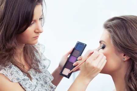 Make-up artist holding eyeshadows palette and applying make-up, selective focus on model s eyeの写真素材
