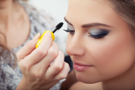 Make-up artist applying mascara on model s eyelashes, close-up, selective focus on lashes and brushの写真素材