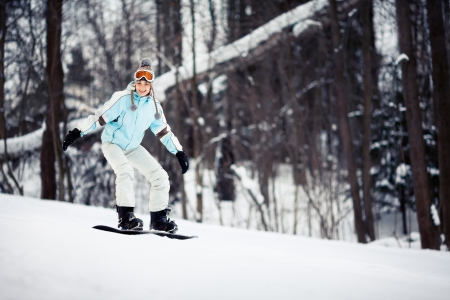 Young female snowboarder sliding down the slope, copy spaceの写真素材