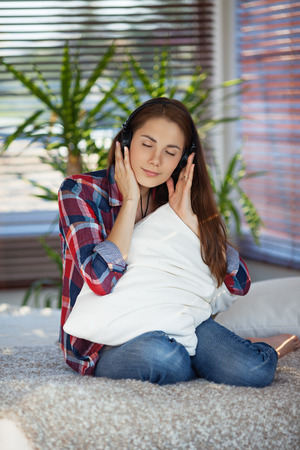 Young woman listening to music on sofa at homeの写真素材