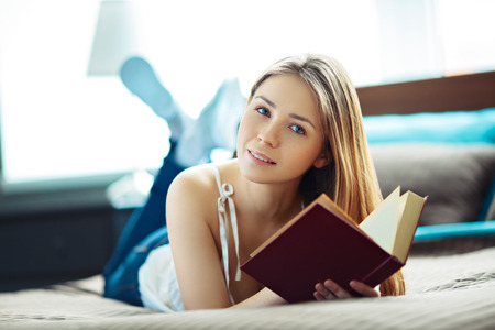 Young woman lying and reading の写真素材