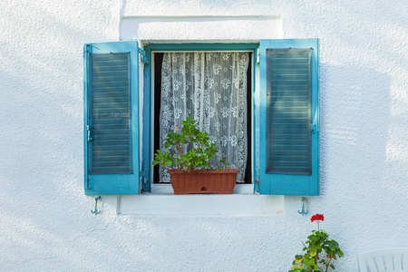 Open window with blue shutters on white wall and flowers, Corfu, Greeceの写真素材