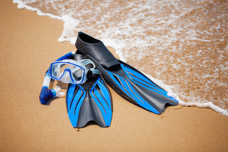 Swim flippers, mask, snorkel in the surf on the sandy beach; selective focusの写真素材