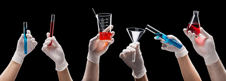 Chemist hands in latex gloves holding laboratory glassware with liquids on black background