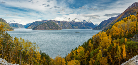 Panoramic view of norwegian fjord, autumn forests and distant snow-capped mountains from aboveの写真素材
