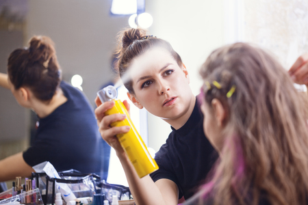 Make-up artist applying hairspray on model's hair,  focus on make-up artistの写真素材