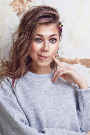 Pretty urban girl in grey sweatshirt making funny faces, grunge wall on backgroundの写真素材