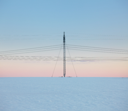 Power line in snow field at pastel sunsetの写真素材