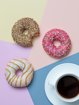 Color block flat lay with black coffee and delicious donuts in pastel colorsの写真素材
