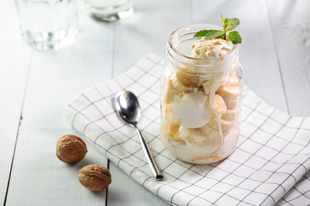 Banana split with vegan ice cream served in glass jar