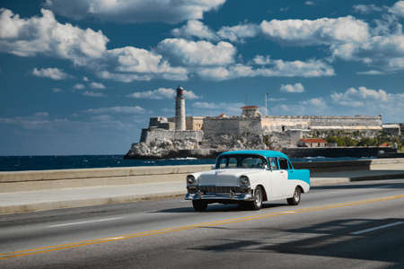 Retro car on the embankment of Havana, Cuba. El morro castle and lighthouse on background, shot with panning.のeditorial素材