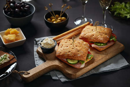 Sandwiches with parma served on cutting board and appetizers aroundの写真素材