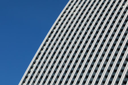 A minimalistic photo of a part of a modern building with repetitive pattern on its exterior stands...