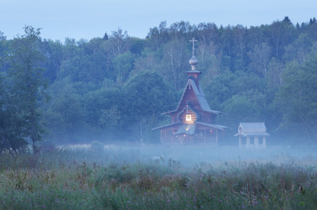 Small wooden Russian-orthodox church fogged on a swamp near holy wellの写真素材