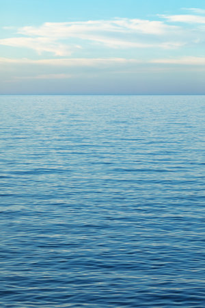 Tranquil seascape featuring gentle ripples and soft pastel hues that stretch to a distant horizon.の写真素材