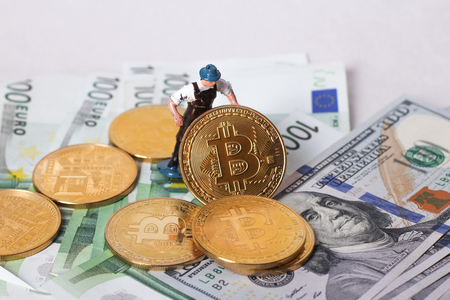 A little miner is digging on golden bitcoin with dollar and graph background. conceptual image of bitcoin mining and trading.の写真素材