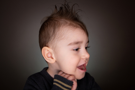 Screaming boy in a brown t-shirt folded his arms behind his head. Isolate on white backgroundの写真素材