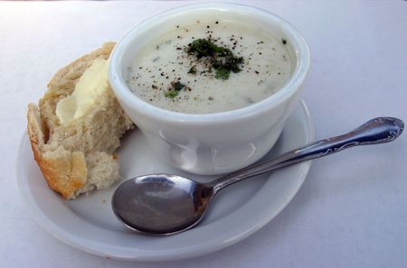 clam chowder in a bowl with french bread and butter