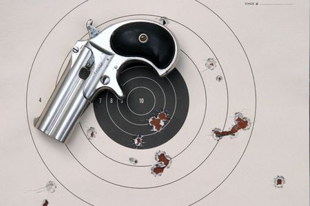 Circa 1889, Model 95, Type II Model 3 Double Derringer on a paper target with bullet holes in itの写真素材