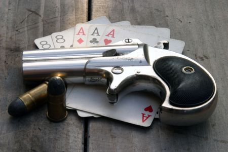 Circa 1889, Model 95, Type II Model 3 Double Derringer on antique wooden table with aces and eights (aka a Dead Mans Hand) and ammoの写真素材