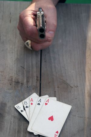 Circa 1889, Model 95, Type II Model 3 Double Derringer on antique wooden table with aces and eights (aka a Dead Mans Hand) and a gamblers hand pointing at the looser "Fer Cheatin'"の写真素材