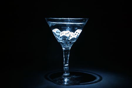 time laps or bulb exposure of a gamblers martini with dice in the glass. illuminated with a small flashlight in a pitch black roomの写真素材