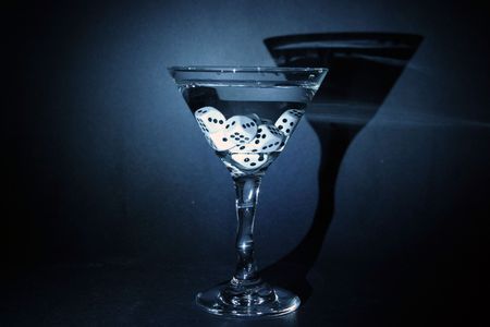 time laps or bulb exposure of a gamblers martini with dice in the glass. illuminated with a small flashlight in a pitch black roomの写真素材