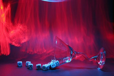 bulb exposure aka Time Laps of a Martini glass with gambling dice in liquid with red orange yellow and blue fiber optic light brushed around in the backgroundの写真素材