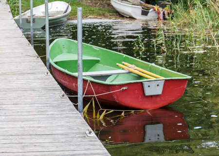 view of the wooden footbridge on the lake shore, fishing boatsの写真素材