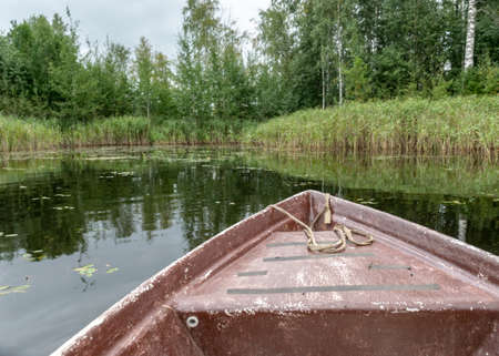 lake view from an old boat, trees on the lake shore, cloudy day, fishing conceptの写真素材