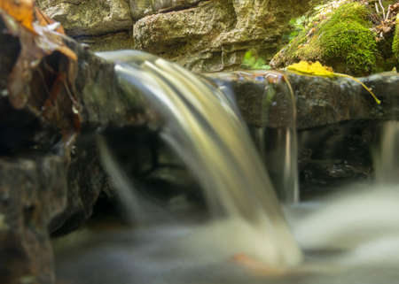 a small rapid river flows through dolomite rocks, long-term exposure, gentle and fuzzy river water, colorful autumn leaves and dry branches in the riverの写真素材