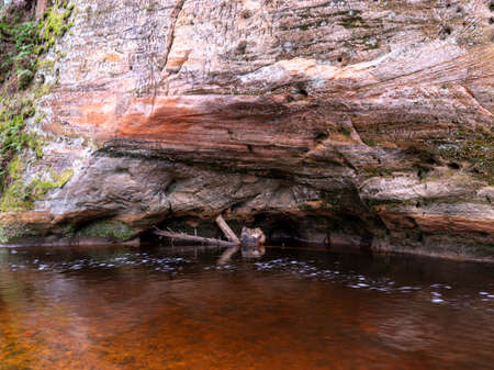 landscape with sandstone rock wall, slow flowing river, tree silhouettesの写真素材