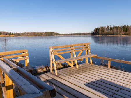 winter landscape with wooden pedestrian platform, frosted bench resting placeの写真素材