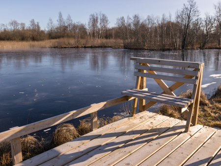 winter landscape with wooden pedestrian platform, frosted bench resting placeの写真素材