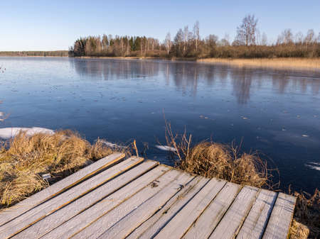 winter landscape with wooden pedestrian platform, frosted bench resting placeの写真素材