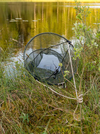 picture with a fish storage net on the lake shore, reflectionsの写真素材
