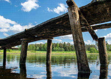 summer landscape with an old wooden footbridge in a small forest lakeの写真素材