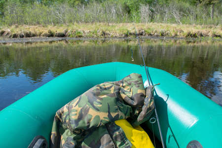 view of the lake landscape from the green rubber boat to the shore, fishing tackle and equipmentの写真素材