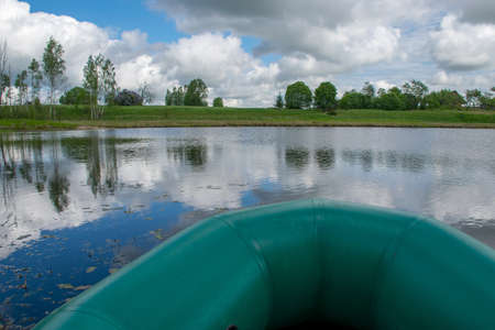view of the lake landscape from the green rubber boat to the shore, fishing tackle and equipmentの写真素材
