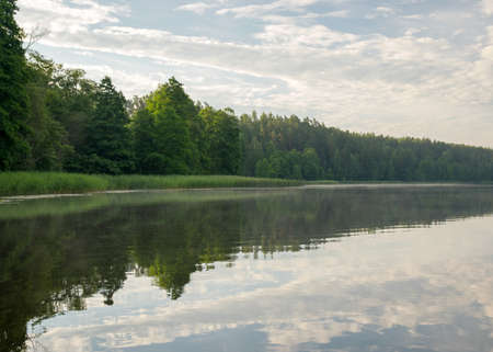 beautiful summer morning landscape on the lake, beautiful clouds and wonderful reflections in the lake mirror, summer morning by the waterの写真素材