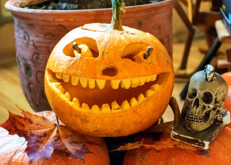 orange halloween pumpkin with carved traditional face, skull symbol, halloween decor, autumnの写真素材
