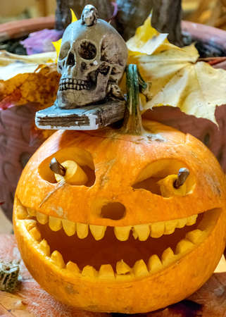 orange halloween pumpkin with carved traditional face, skull symbol, halloween decor, autumnの写真素材
