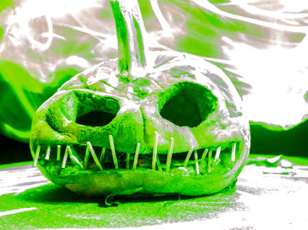 terrible a burning carved pumpkin with a scary face and colorful light drawings in a dark background, suitable for Halloweenの写真素材