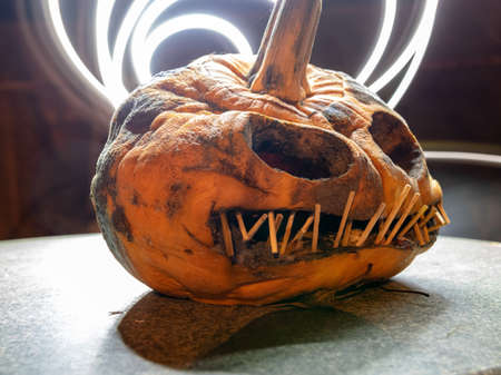 terrible a burning carved pumpkin with a scary face and colorful light drawings in a dark background, suitable for Halloweenの写真素材
