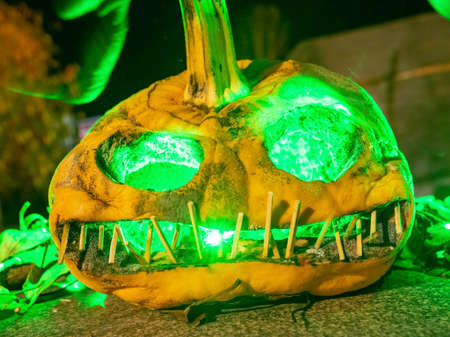 terrible a burning carved pumpkin with a scary face and colorful light drawings in a dark background, suitable for Halloweenの写真素材