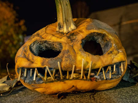 terrible a burning carved pumpkin with a scary face and colorful light drawings in a dark background, suitable for Halloweenの写真素材