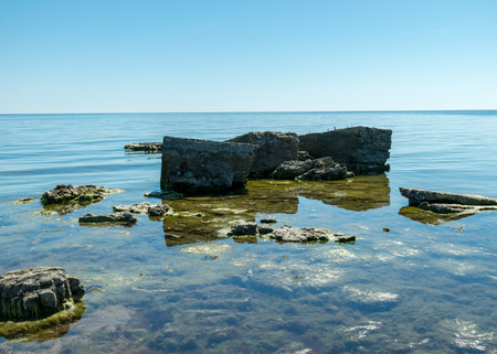 sunny summer landscape with a rocky sea shore, remnants of an old concrete structure in the water, Saaremaa Island, Sorves Peninsula, Estoniaの写真素材