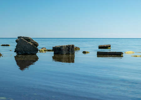 sunny summer landscape with a rocky sea shore, remnants of an old concrete structure in the water, Saaremaa Island, Sorves Peninsula, Estoniaの写真素材