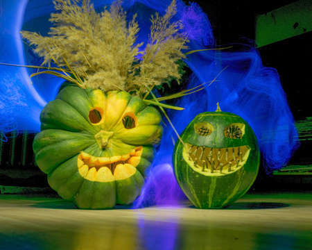 Preparing for Halloween, pumpkin carving, green carved pumpkins for Halloween, colorful light painting background, Halloween Jack o Lanterns, autumnの写真素材