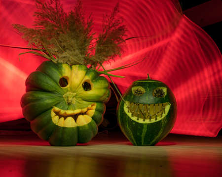Preparing for Halloween, pumpkin carving, green carved pumpkins for Halloween, colorful light painting background, Halloween Jack o Lanterns, autumnの写真素材
